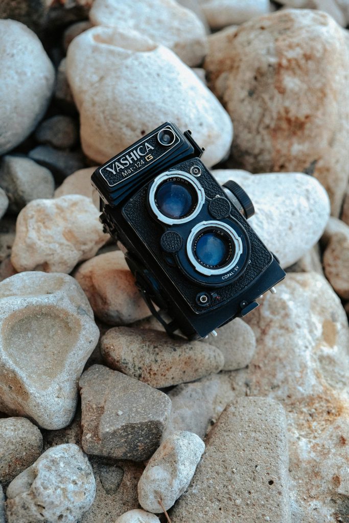 Close-up of a vintage Yashica camera on textured rocks, perfect for photography enthusiasts.