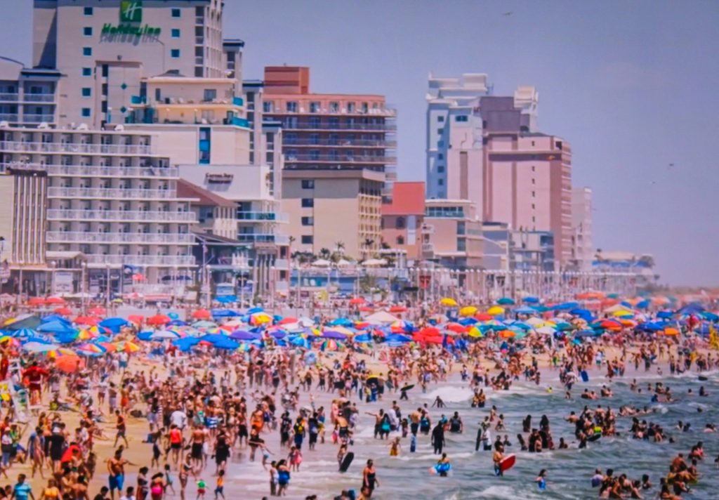 un gran grupo de personas en una playa con sombrillas
