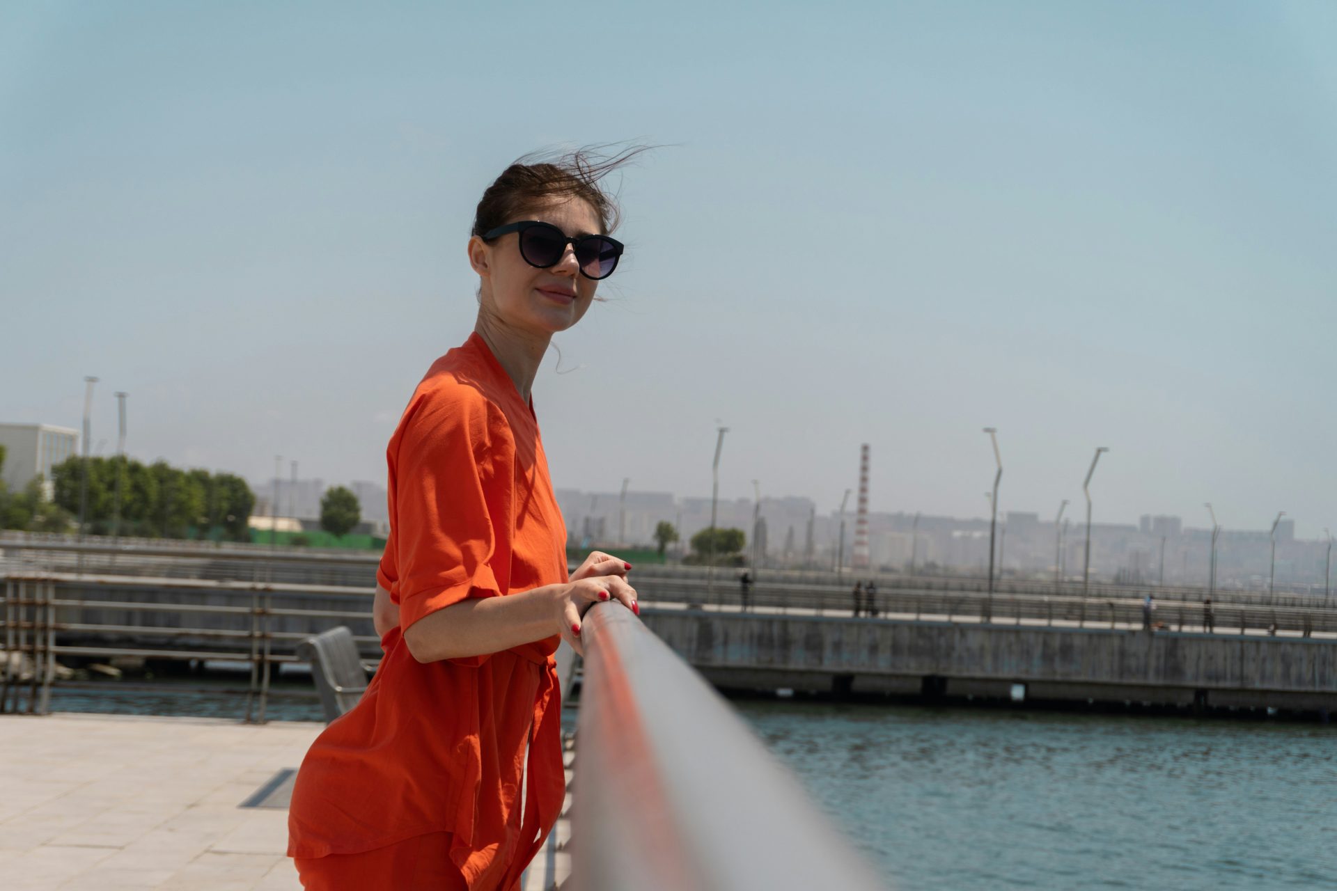 Mujer con camisa naranja junto al agua.